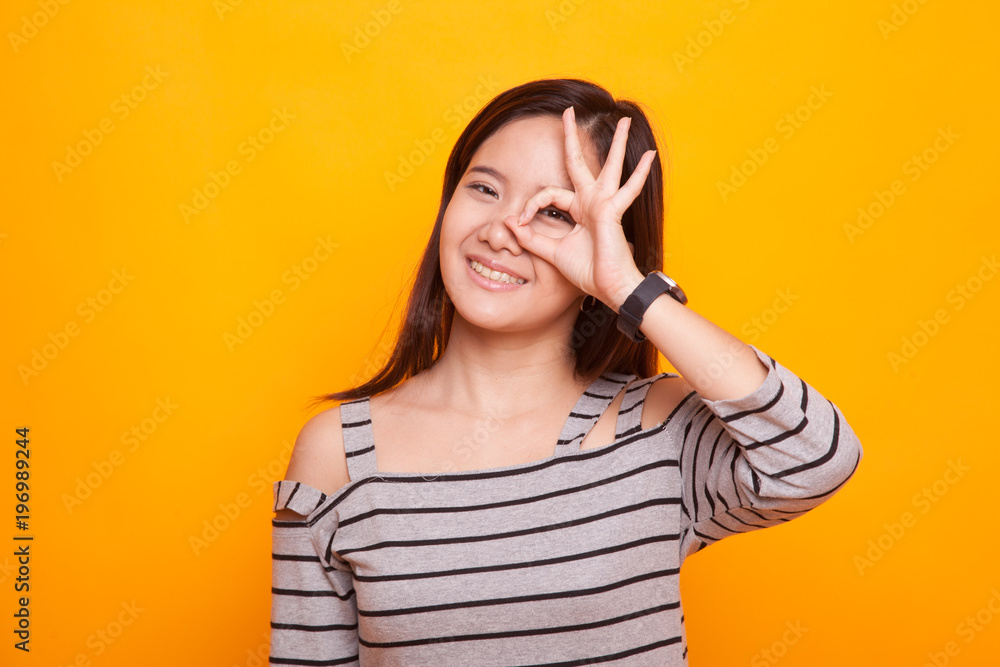 Beautiful young Asian woman show OK sign over her eye. Beautiful young Asian woman show OK sign over her eye.