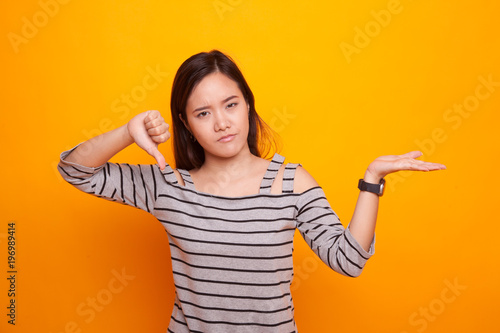 Young Asian woman show palm hand and thumbs down.