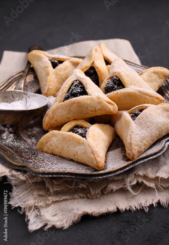 Hamantaschen cookies with poppy seed and risins and icing sugar on a plate, cooked for Jewish festival of Purim. photo