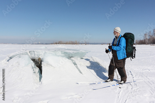 Man in a blue  jacket on ski looking at the ice breaking on the river,Ob Reservoir, Russia