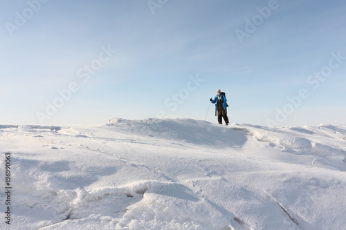 Man in a blue jacket with a backpack is skiing on the ice of the frozen river,Ob Reservoir, Russia