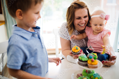Happy children with mother eating cupcakes