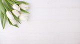 Bouquet of white tulips on a white wooden table, copy space. Easter.