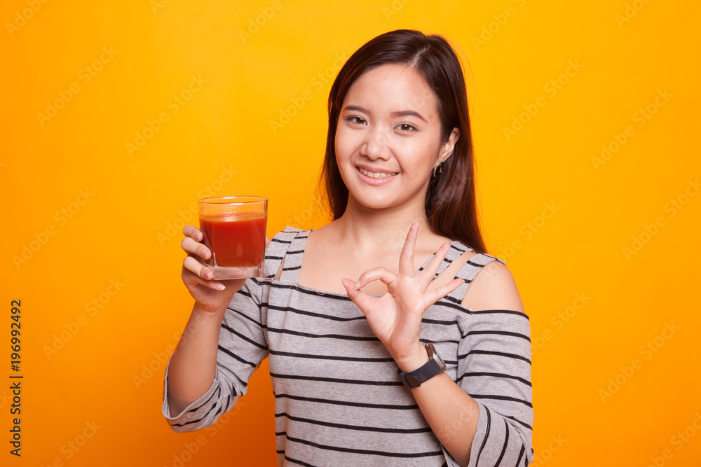 Young Asian woman show OK with tomato juice. Young Asian woman show OK with tomato juice.