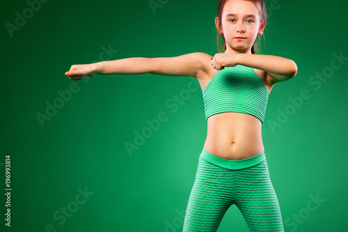 Kid girl doing fitness exercises on green background © Mike Orlov