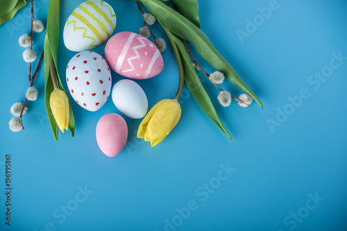 Colorful Easter eggs with yellow Tulip hand painted on a blue background. Holiday spring card