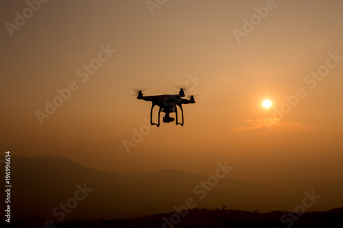 Drone silhouette flying in sunset landscape.  © sanee