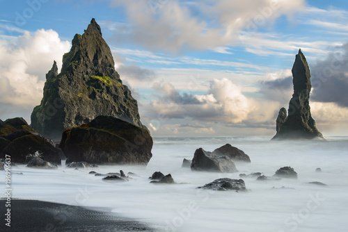 the black beach of Reynisfjara in Iceland with giant rocks and a dangerous breakwater, taken with time exposure.