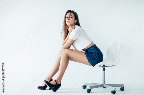 Beautiful sensual woman sitting on chair on white background