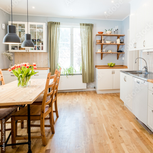 beautiful kitchen interior with green curtains orange tulips on the table and light grey walls