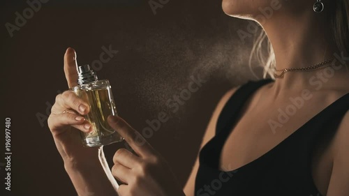 Sensual girl spraying fragrance in slow motion, with scent particles. Concept of sensual feminine scent.