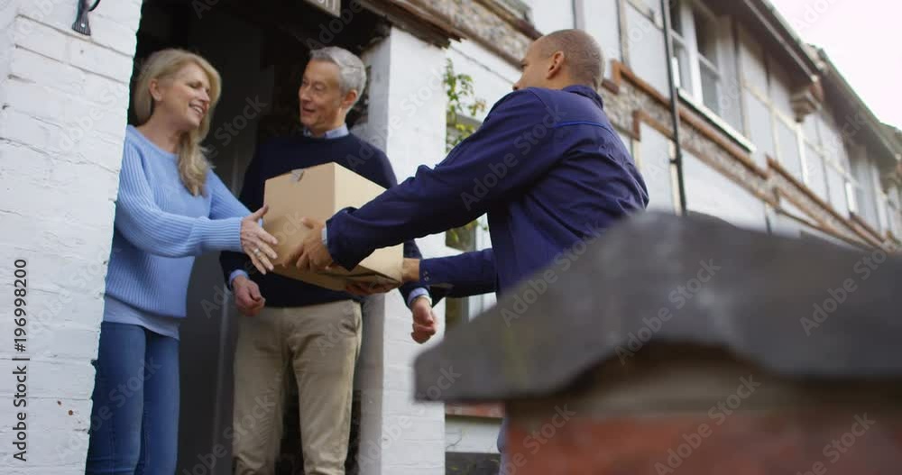 4K Smiling couple taking package from delivery man & signing on digital device 4K Smiling couple taking package from delivery man & signing on digital device