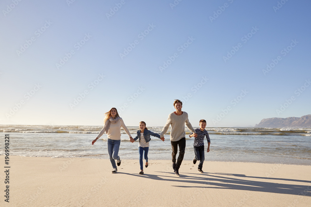 Family On Winter Beach Holding Hands And Running Towards Camera