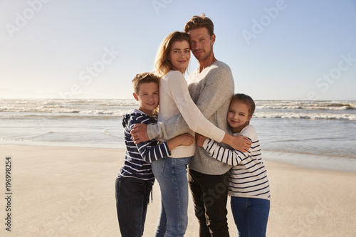 Portrait Of Loving Family Embracing On Winter Beach