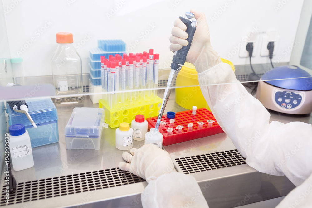 The assistant in the laboratory conducts an analysis of saliva for the isolation of DNA, close-up on hands with pipette and test tubes - obrazy, fototapety, plakaty 