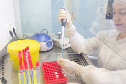 The assistant in the laboratory conducts an analysis of saliva for the isolation of DNA, close-up on hands with pipette and test tubes