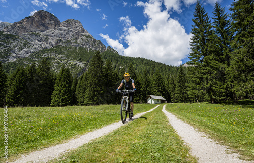 Tourist cycling in Cortina d'Ampezzo, stunning rocky mountains on the background. Woman riding MTB enduro flow trail. South Tyrol province of Italy, Dolomites. © Gorilla