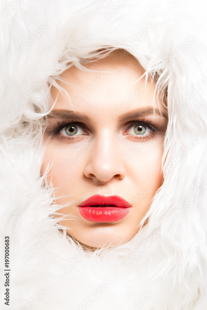 Fashion studio portrait of a beautiful fair-skinned woman in white fur closeup. Winter beauty in luxury. Beauty woman in luxury fur. Fashion model posing in eco fur.