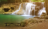 waterfall with relax long wood chair and clear blue and green water with tree and root in jungle for travel on summer holiday at Huay Mae Khamin waterfall and nature landscape background with sunlight