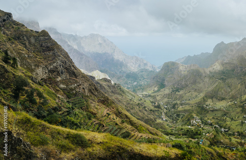 Gorgeous panorama view of a fertile Paul valley. Agriculture terraces in vertical valley sides  rugged peaks and motion clouds on horizon
