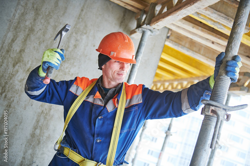 Builder installing or dismantling pole support for concrete monolithic formwork at housebuilding photo