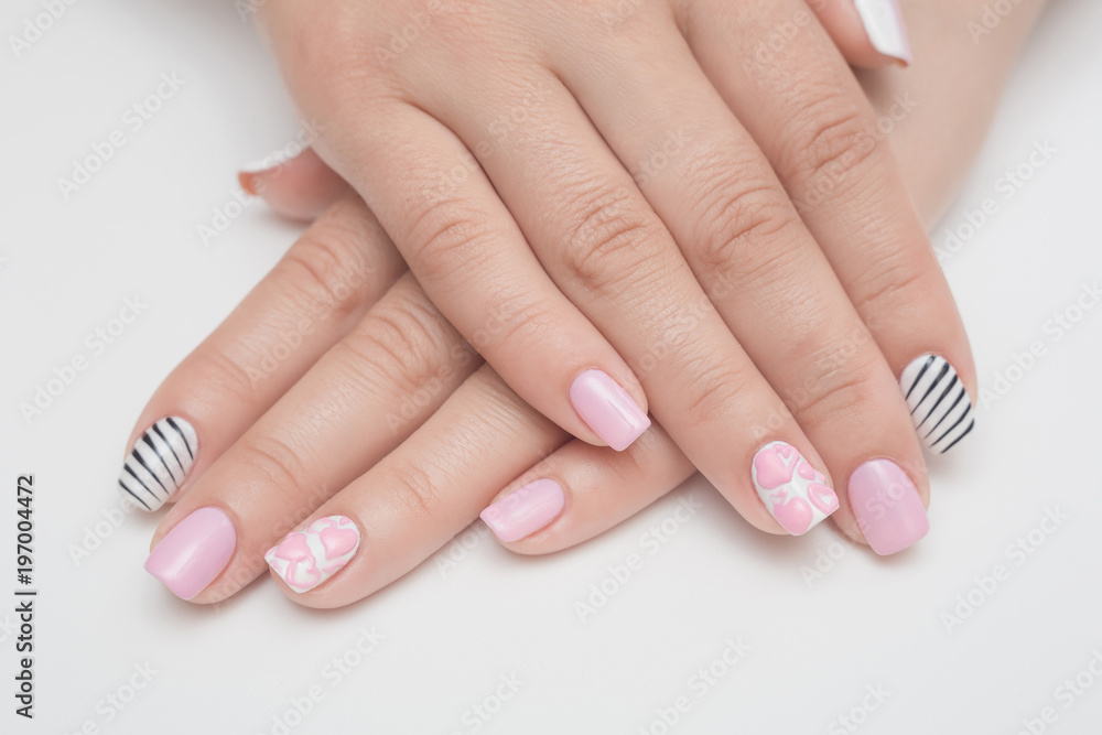 Manicure with rhinestones in the shape of hearts and pink balls on white and red nail Polish on a white background. Manicure with rhinestones in the shape of hearts and pink balls on white and red nail Polish on a white background.