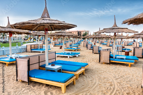 A lot of chaise lounges with blue mattresses on a luxurious beach. Umbrellas for protection from the sun. photo