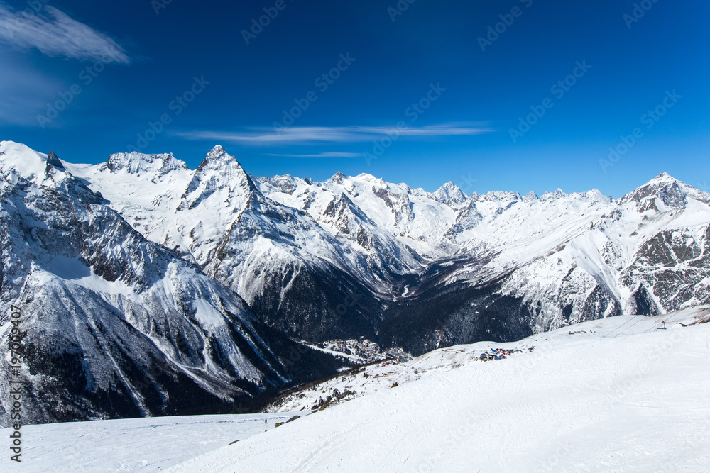 snow-capped alpine mountain ranges extending into the distance and the village below. panorama