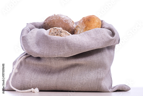 Homemade bread in a natural linen bag for storage, isolated on white background
