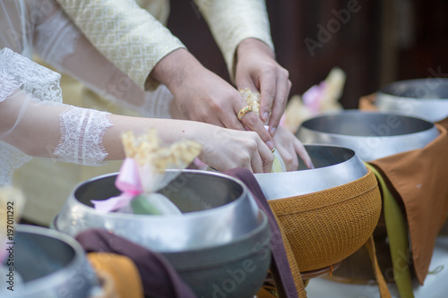 Bride and Groom give alms food to a Buddhist monk in traditional thai wedding ceremony