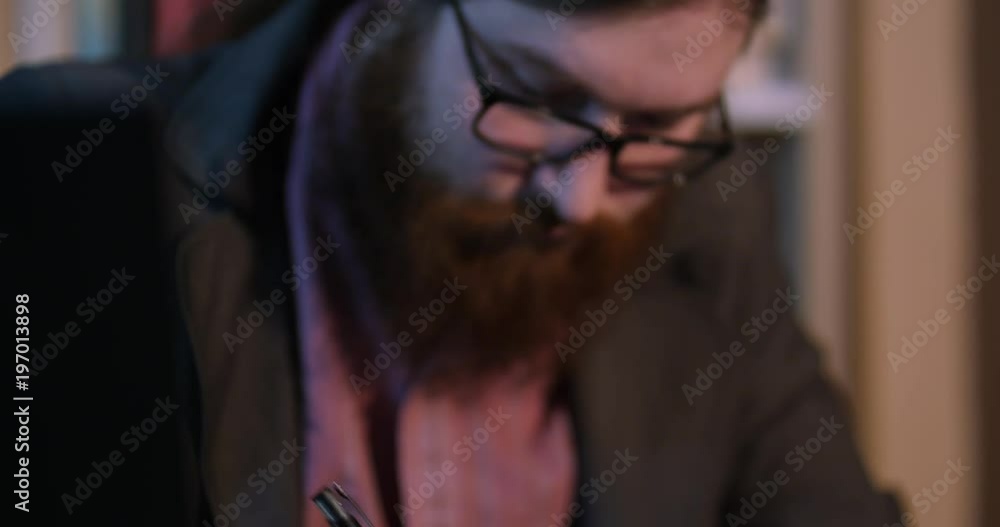 A young bearded man signs papers near the fireplace paper closeup A young bearded man signs papers near the fireplace paper closeup