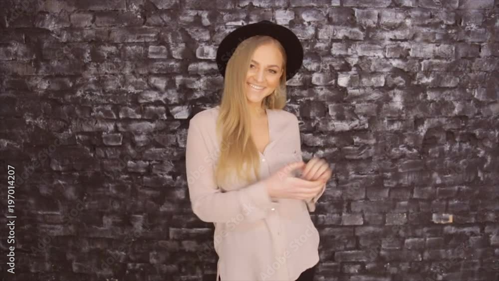 Model in a black hat and a gray shirt posing against a brick wall background Model in a black hat and a gray shirt posing against a brick wall background