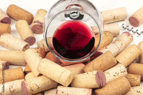 A closeup photo of a glass of red wine with wine corks