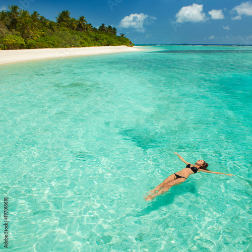 Woman swim and relax in the sea. Happy island lifestyle. White sand  crystal-blue sea of tropical beach. Vacation at Paradise. Ocean beach relax  travel to Maldives islands
