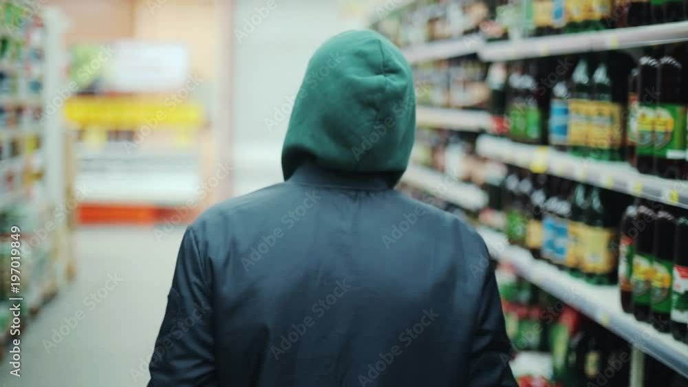 Portrait man steals bottle of alcohol in supermarket go away shot behind shoplifting larceny technology crime store theft criminal customer illegal retail poor looting lifting security shop consumer Portrait man steals bottle of alcohol in supermarket go away shot behind shoplifting larceny technology crime store theft criminal customer illegal retail poor looting lifting security shop consumer