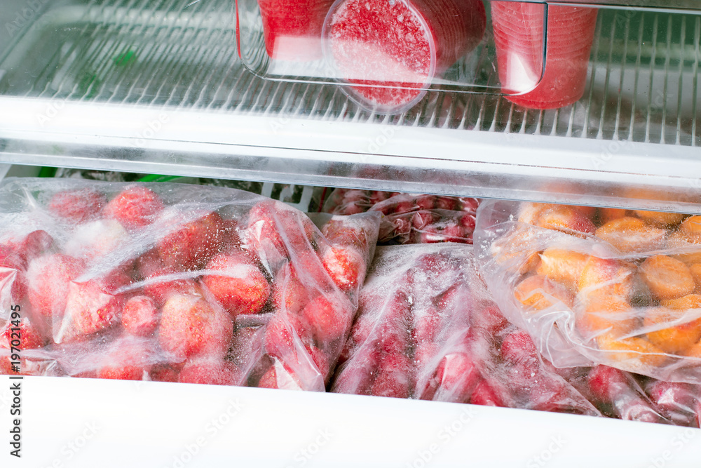 Frozen berries and fruits in bags in freezer, close up
