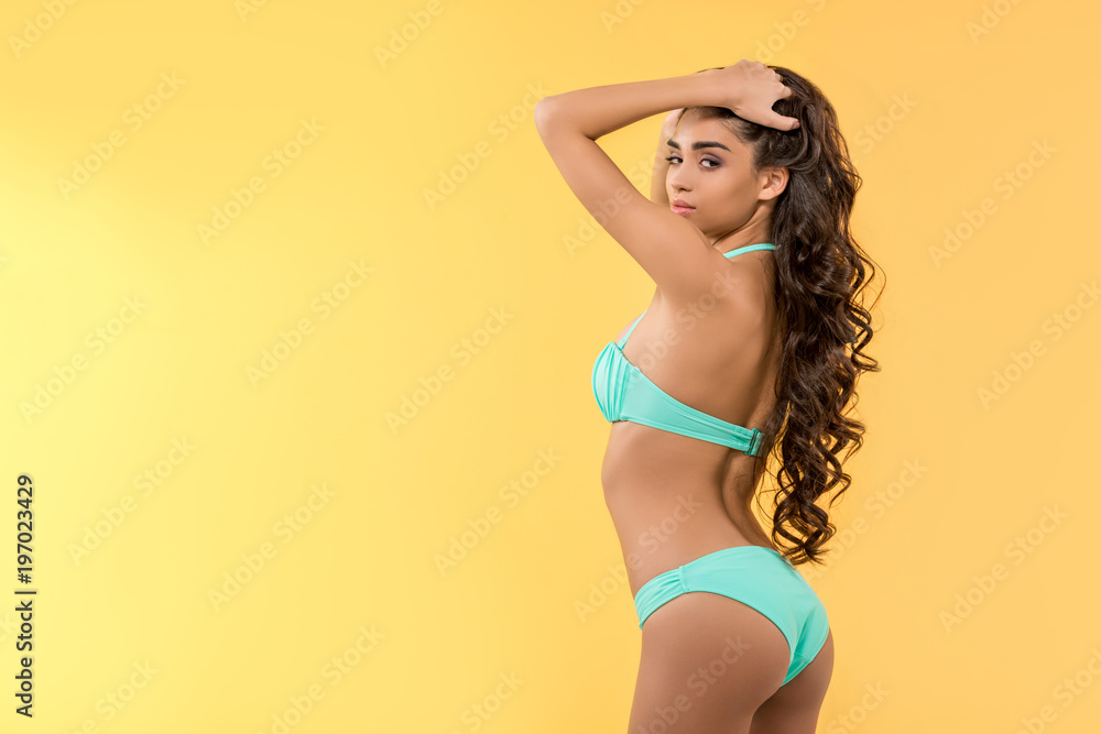 beautiful slim girl posing in bikini, isolated on yellow beautiful slim girl posing in bikini, isolated on yellow