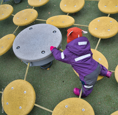 a child in purple overals playing on the playfield. photo