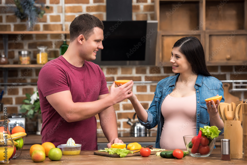 happy young pregnant couple squeezing fresh juice together at home happy young pregnant couple squeezing fresh juice together at home