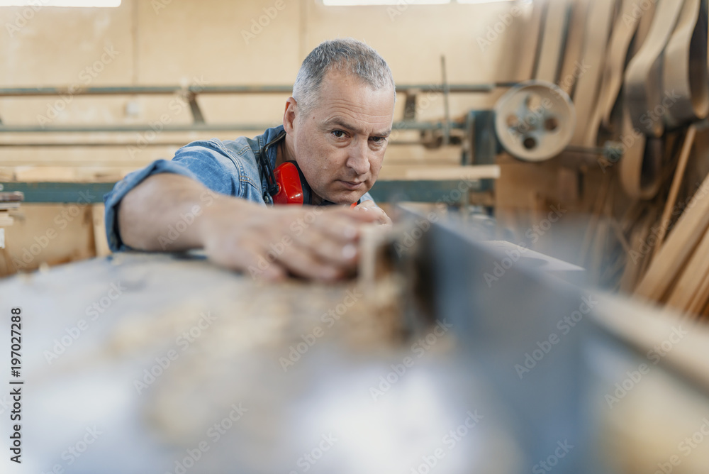 A carpenter works on woodworking the machine tool. Carpenter working on woodworking machines in carpentry shop.
