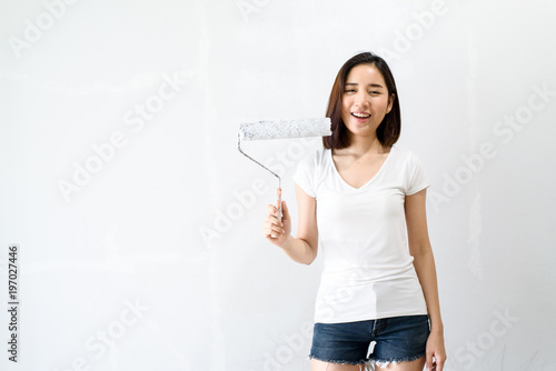 Young Asian woman painting on a white wall