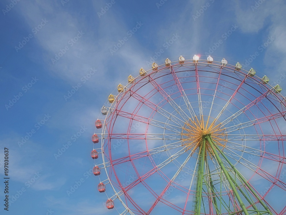 青空に立つ遊園地のカラフルな観覧車