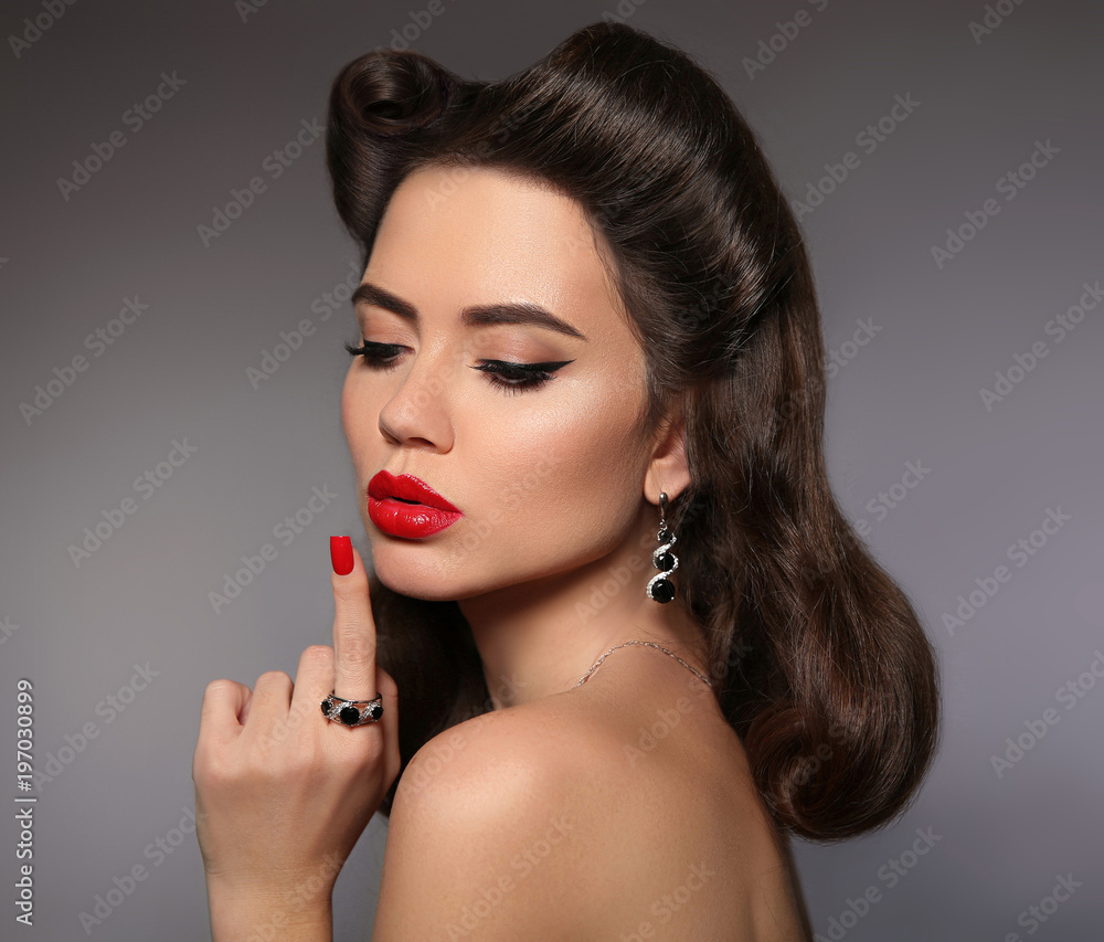 Beauty makeup. Fashion women jewelry. Retro woman portrait with red lips  make-up and curly pinup hair style isolated on gray background. Pin up  girl. Stock Photo