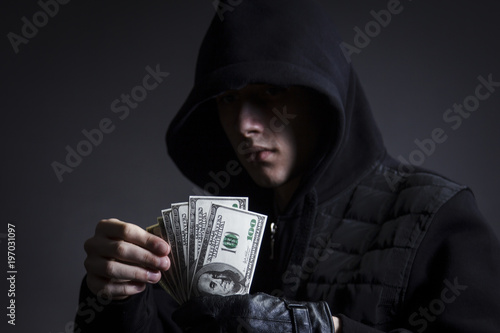 The swindler in the hood counts the stolen money photo