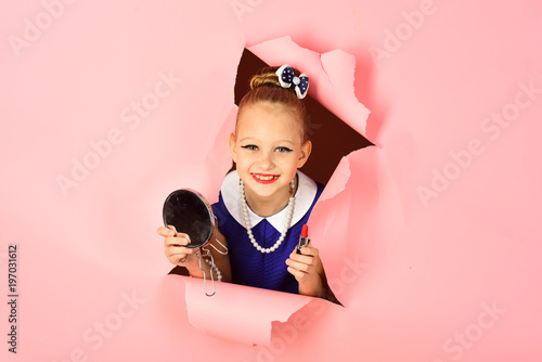 Fashion and beauty, pinup style, childhood. Retro girl, fashion, cosmetics, beauty. Makeup, retro look, hairdresser, pin up. Child girl in stylish dress, makeup. Little girl hold lipstick and mirror.