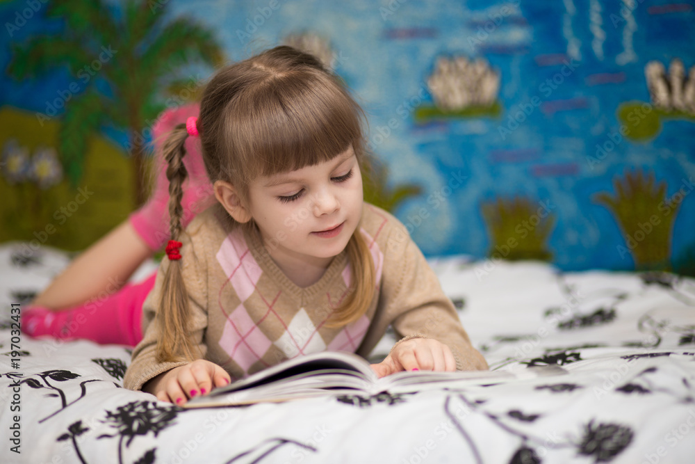 Little cheerful girl read book in bed. Concept of kids knowledge Little cheerful girl read book in bed. Concept of kids knowledge