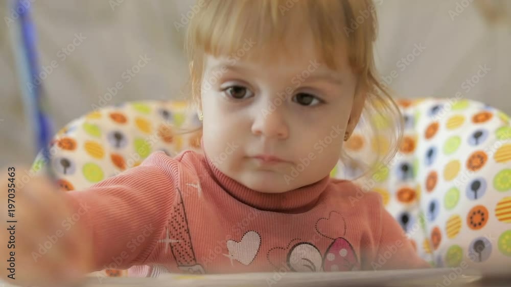 Beautiful two years old girl draws pictures with a paintbrush. Cute blonde child. Brown eyes. Close up. FEW SHOTS Beautiful two years old girl draws pictures with a paintbrush. Cute blonde child. Brown eyes. Close up. FEW SHOTS