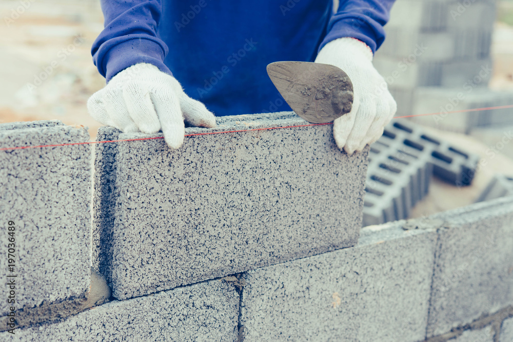 Bricklayer worker installing brick masonry.