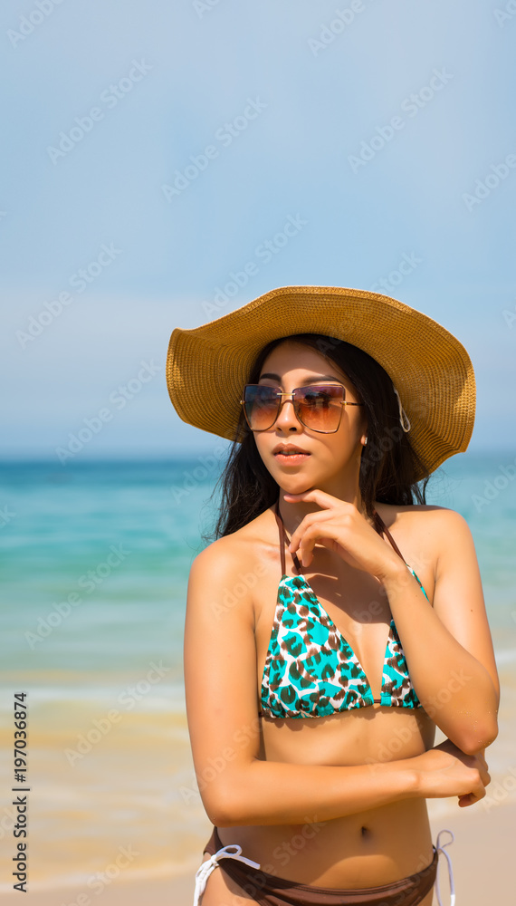 Asian woman on beach are posted to take a photo while happy vacation or weekend on sunny days and nice weather in travel and holiday concept.