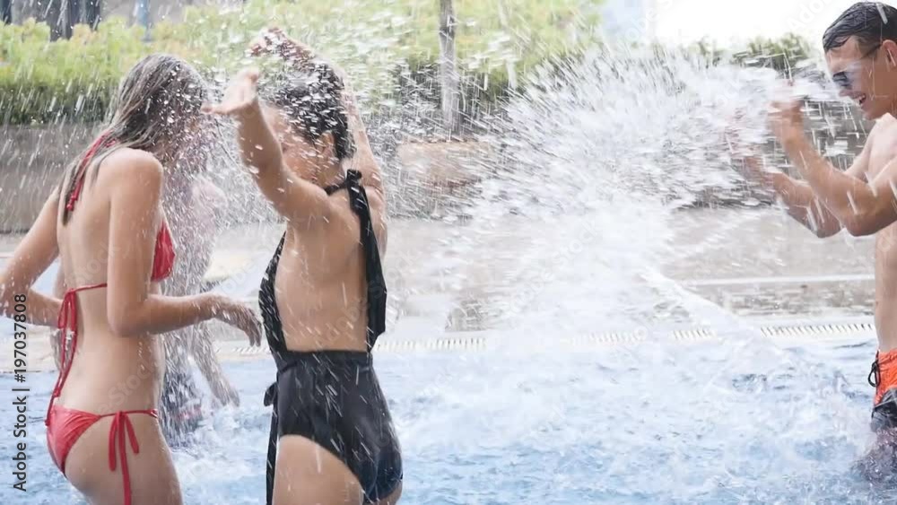 Group of friends enjoying vacation in summer time. Young people having fun in swimming pool Group of friends enjoying vacation in summer time. Young people having fun in swimming pool